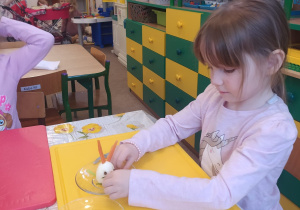 dziewczynka przy stoliku ozdabia jajko