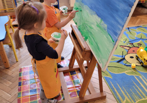 Chłopiec i dziewczynka malują farbami płótno