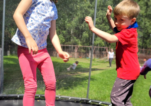 chlopiec i dziewczynka skaczą na trampolinie
