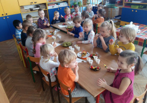 Dzieci siedzą przy stolikach