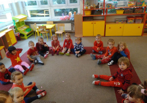 Dzieci ubrane w czerwone ubranka na dywanie