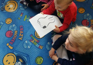 Dzieci na dywanie oglądają ilustracje zęba