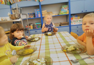 Dzieci przy stoliku jedzą obiad
