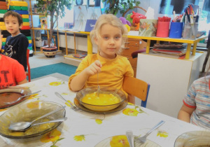 Dziewczynka przy stoliku je zupę