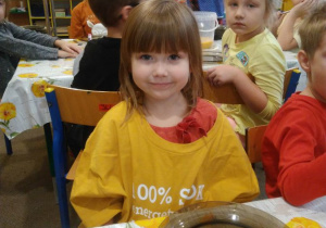 Dziewczynka w żółtej bluzce przy stoliku