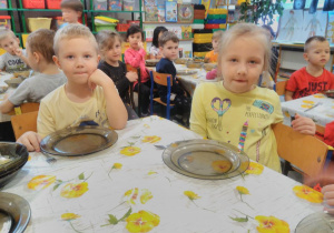Dzieci przy stoliku jedzą obiad