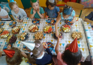 Dzieci przy stole jedzą owoce