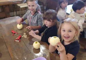 dzieci z jabłkami siedzą przy stoliku