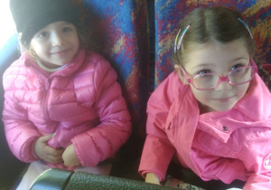 dwie dziewczynki w różówych kurtkach w autokarze