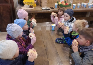 dzieci przy stoliku jedzą kiełbaski