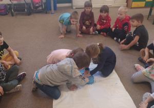 dzieci na dywanie obserwują piasek kinestetyczny