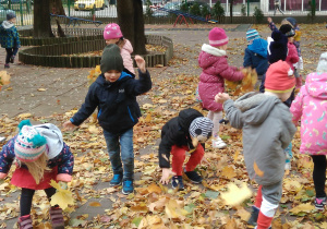dzieci w ogrodzie podrzucają liście