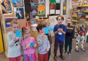 dzieci stoją z niebieskimi karteczkami w dłoniach
