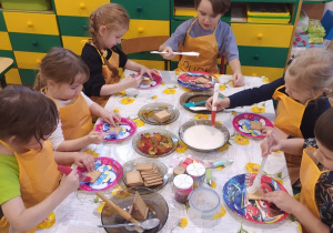 dzieci przy stoliku dekorują ciasteczka