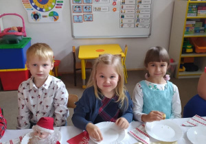 dwie dziewczynki i chłopiec siedzą przy stoliku