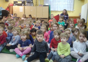 Dzieci siedzą w sali gimnastycznej