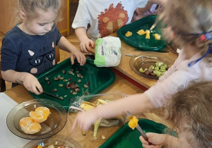 dzieci kroją i układają owoce na talerzach