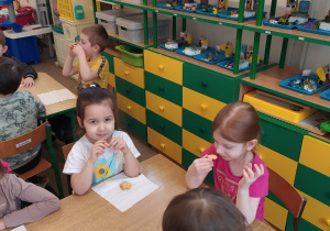 dzieci przy stoliku jedzą ciasteczka