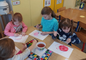 dzieci przy stoliku malują farbami